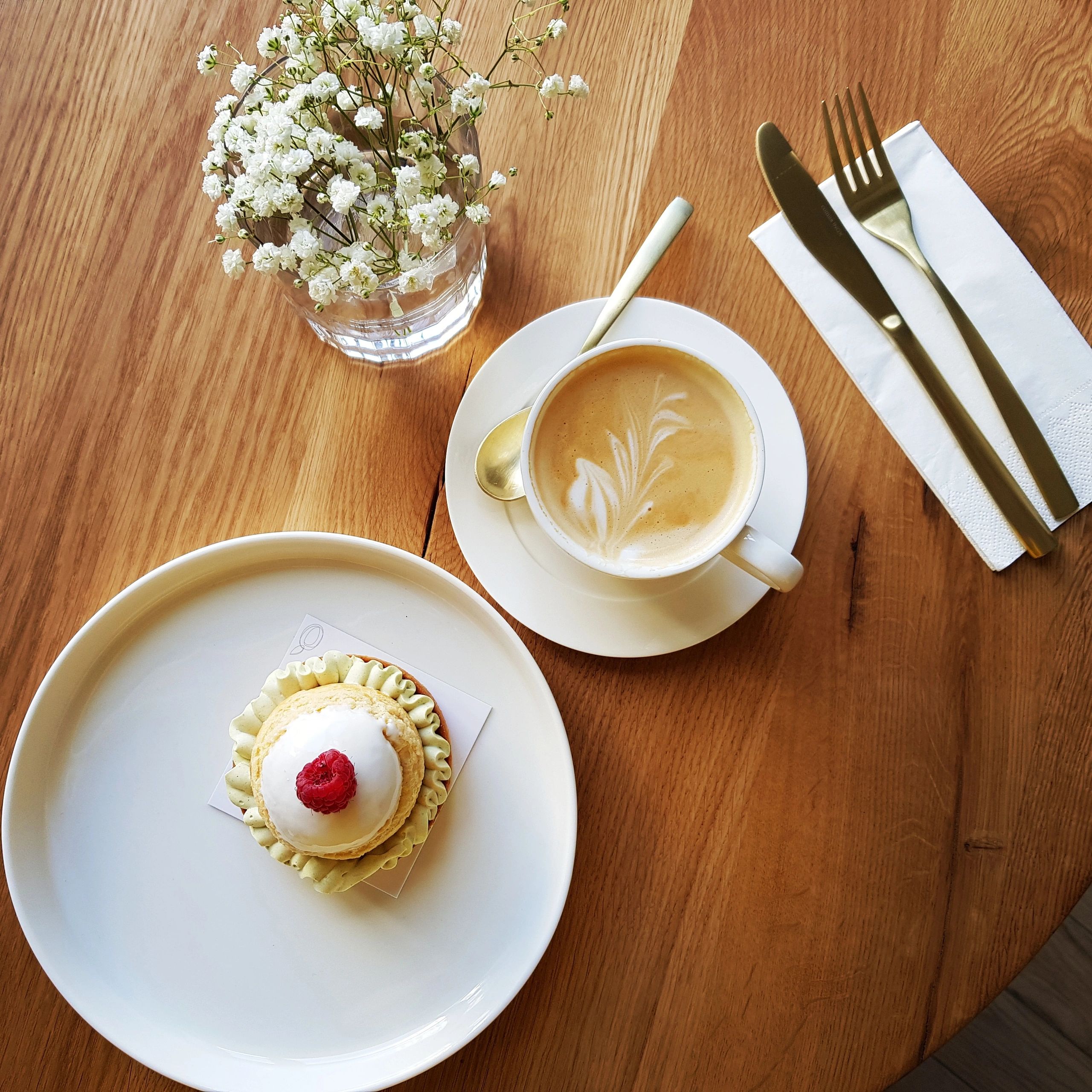 Raspberry pistachio tartlet with cappuccino and elegant gold cutlery