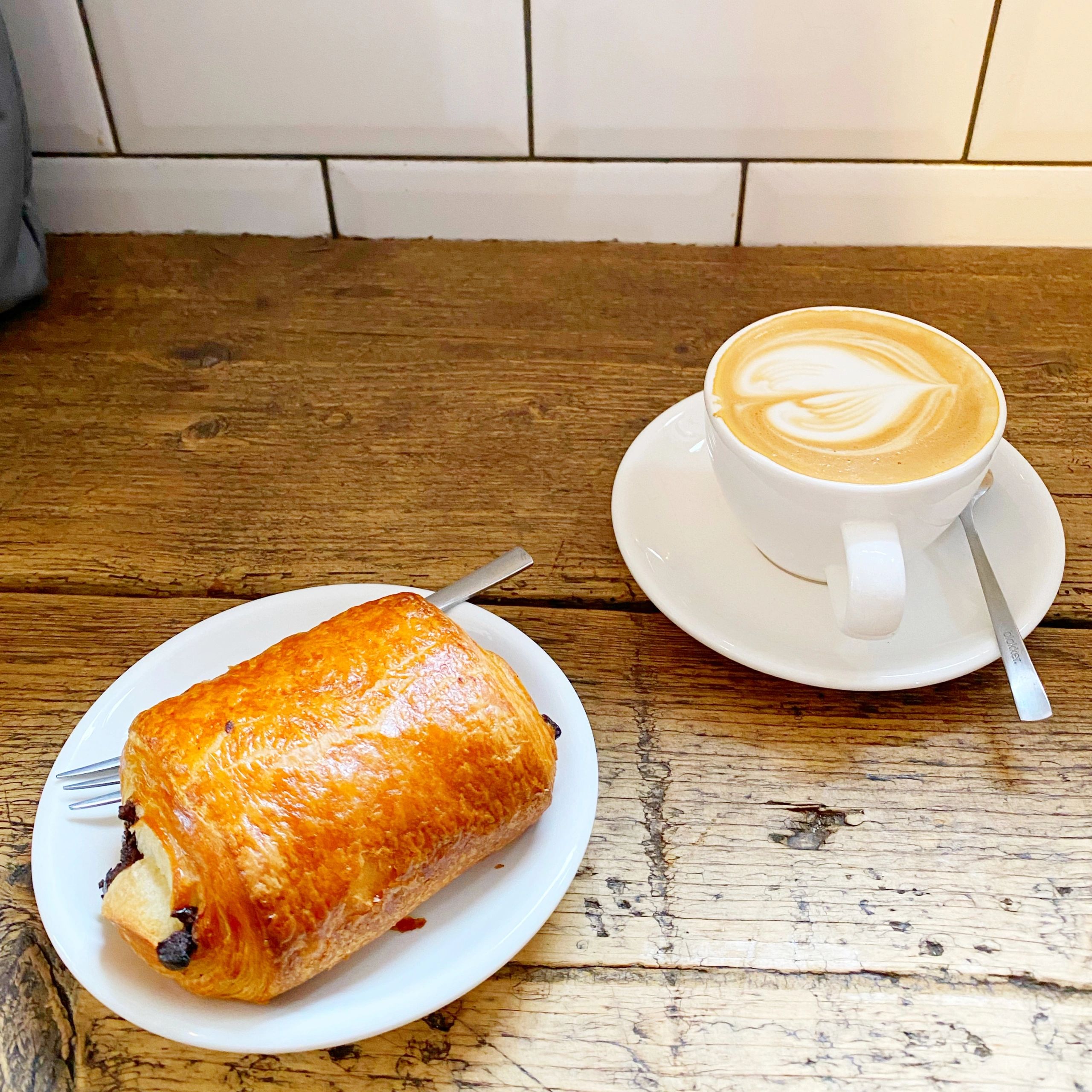 Pain au chocolat with flat white in a chic café presentation
