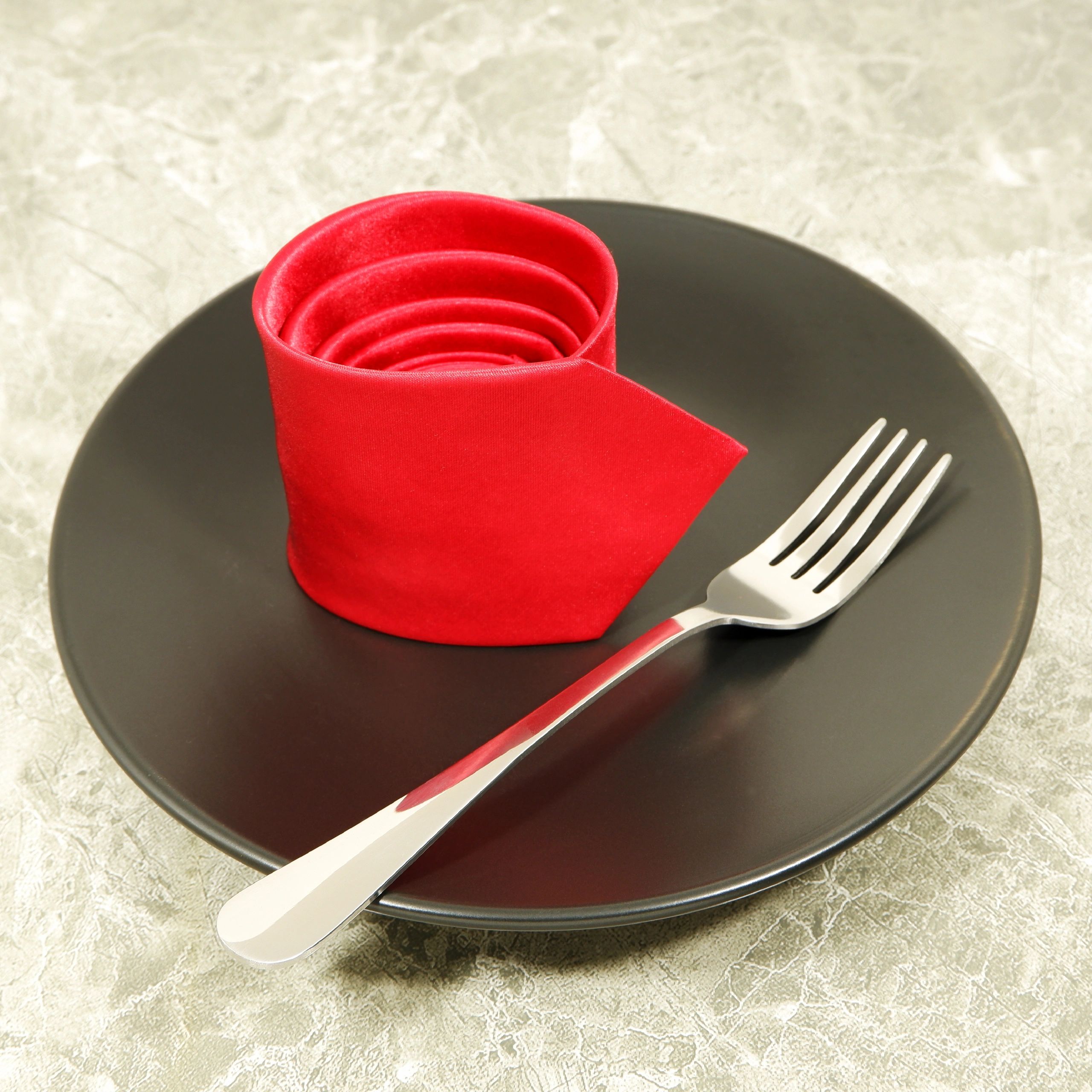 Elegant place setting detail with plate, fork, and necktie styling