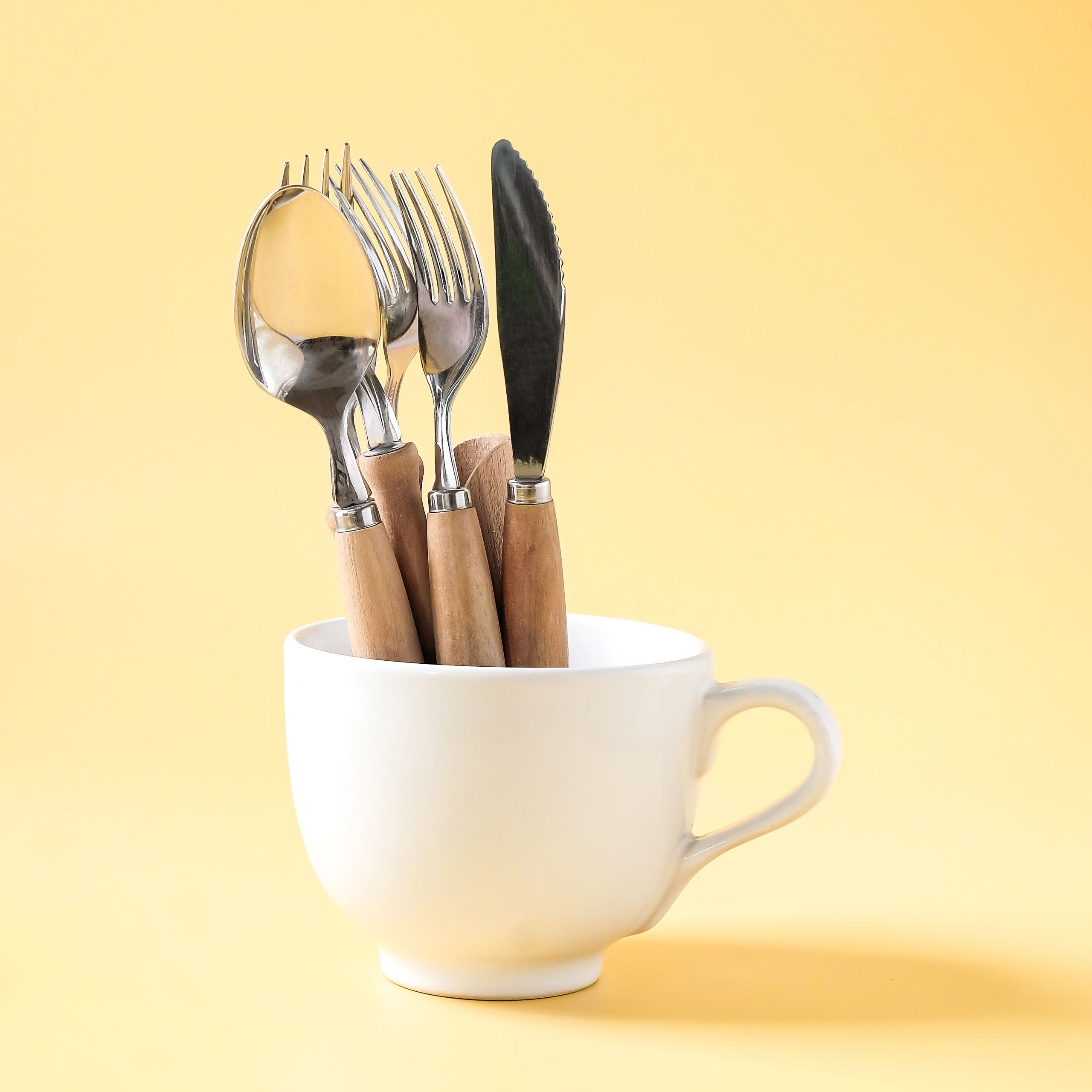 Coffee cup with fork and knife in a minimalist editorial composition